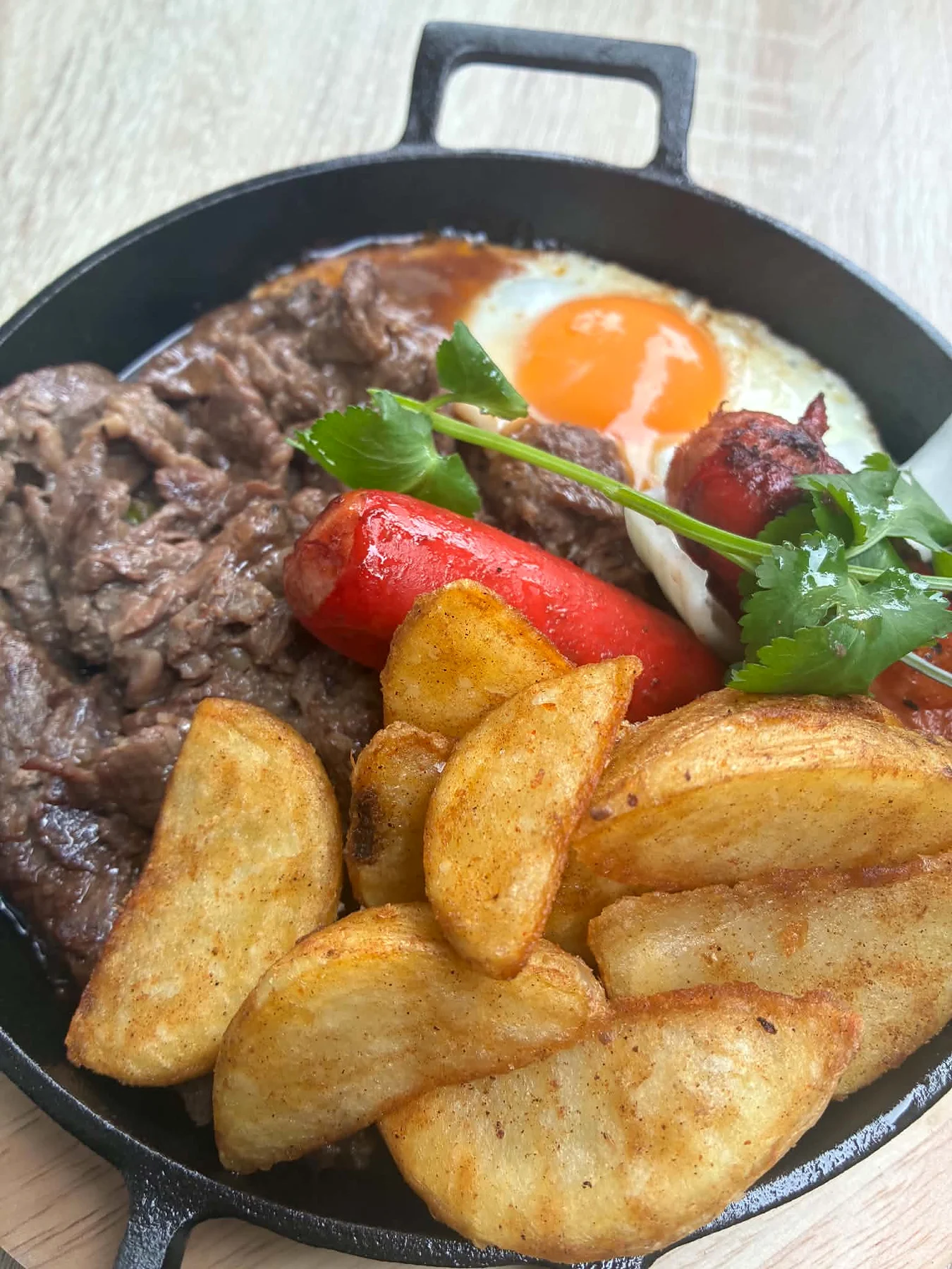 Signature Bò Né with sizzling beef, eggs, sausage and crisp potatoes