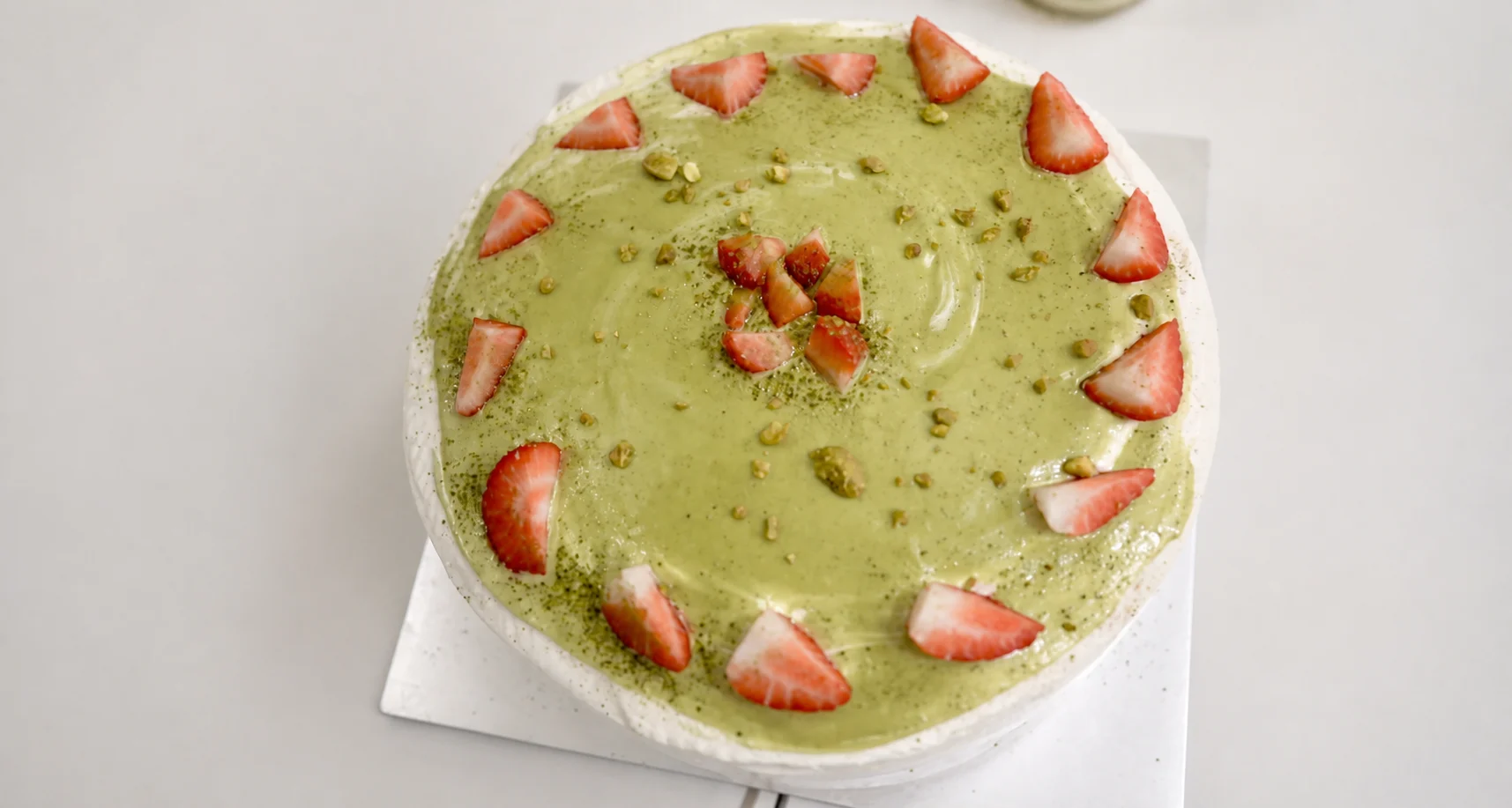 Whole matcha cake finished with strawberries and pistachios